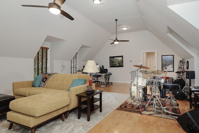 living room with hardwood / wood-style floors, a textured ceiling, ceiling fan, and lofted ceiling