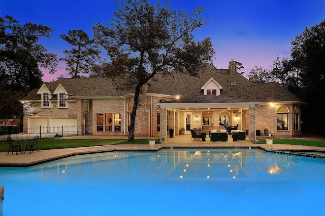 pool at dusk featuring an outdoor living space and a patio area