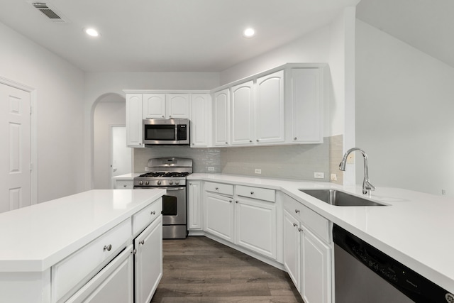 kitchen featuring sink, dark wood-type flooring, stainless steel appliances, decorative backsplash, and white cabinets