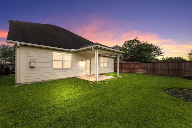 back house at dusk with a yard and a patio