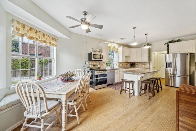 dining space with light hardwood / wood-style floors, ceiling fan, and sink