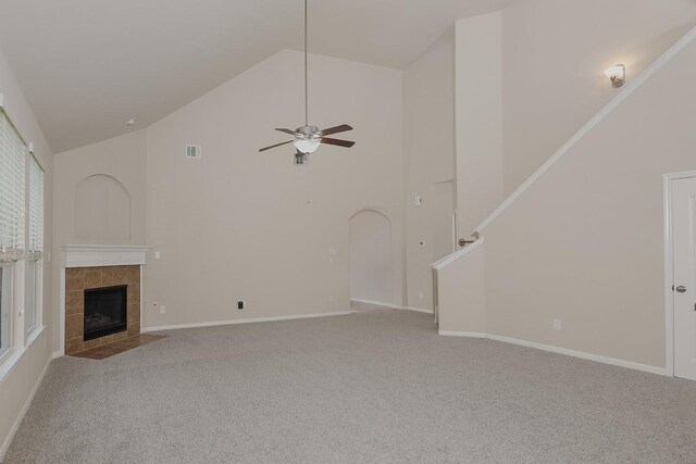 unfurnished living room with a tile fireplace, light carpet, high vaulted ceiling, and ceiling fan