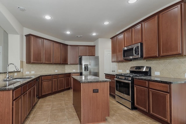 kitchen featuring kitchen peninsula, appliances with stainless steel finishes, dark stone counters, sink, and a center island