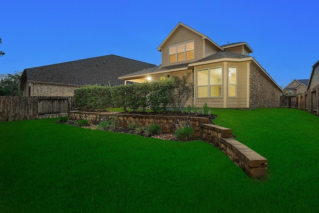 back house at dusk featuring a yard