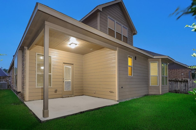 rear view of property featuring a lawn, central air condition unit, and a patio