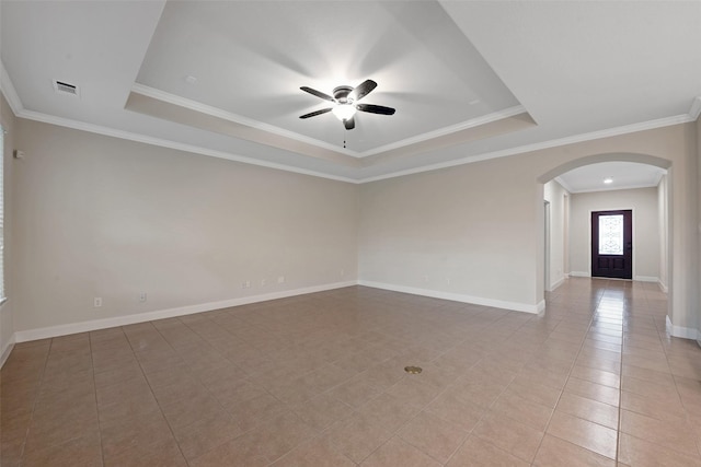 tiled empty room featuring ceiling fan, ornamental molding, and a tray ceiling