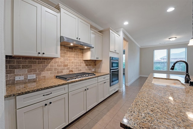 kitchen featuring light stone countertops, white cabinetry, sink, stainless steel appliances, and ornamental molding