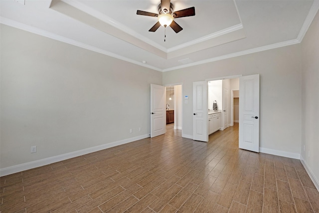 unfurnished bedroom with a tray ceiling, ceiling fan, and ornamental molding