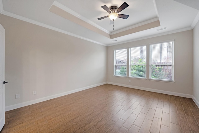 spare room featuring a raised ceiling, ceiling fan, crown molding, and light wood-type flooring