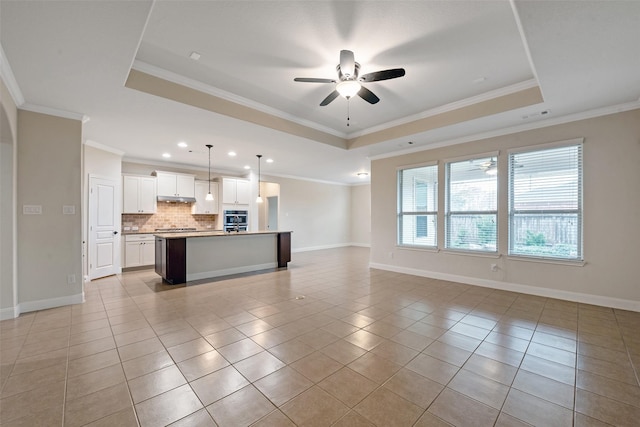 unfurnished living room with a tray ceiling, ceiling fan, crown molding, and light tile patterned flooring