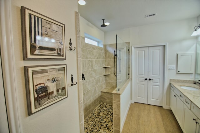 bathroom with a tile shower, hardwood / wood-style floors, and vanity