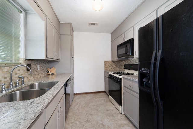 kitchen featuring light stone countertops, sink, backsplash, and black appliances