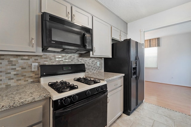 kitchen with black appliances, decorative backsplash, white cabinets, and light stone countertops