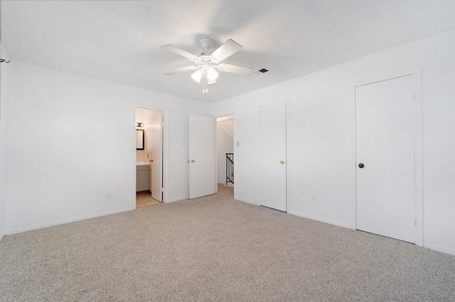 unfurnished bedroom with connected bathroom, light colored carpet, and ceiling fan