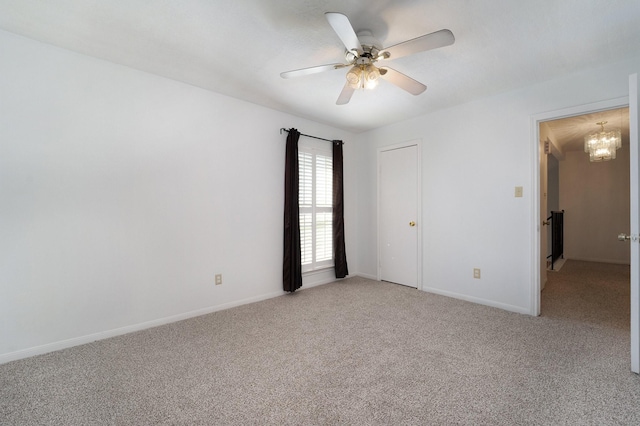 empty room featuring light colored carpet and ceiling fan with notable chandelier