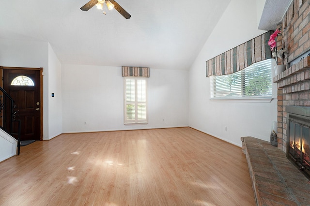 unfurnished living room featuring light wood-type flooring, a brick fireplace, ceiling fan, and lofted ceiling