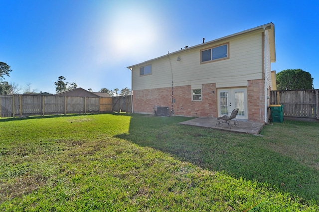 rear view of property with a patio area, a yard, french doors, and central AC