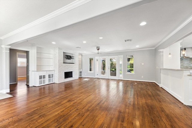 unfurnished living room with a fireplace, built in shelves, ceiling fan, and ornamental molding