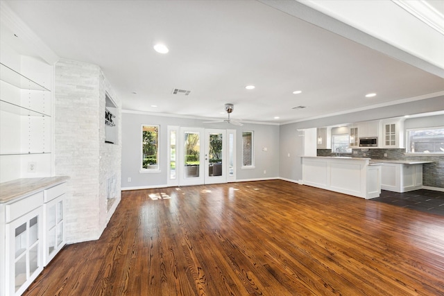 unfurnished living room with ceiling fan, french doors, sink, dark wood-type flooring, and crown molding