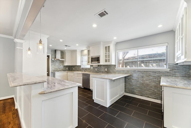 kitchen with wall chimney range hood, hanging light fixtures, appliances with stainless steel finishes, white cabinetry, and a breakfast bar area