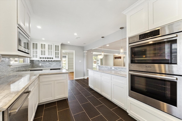 kitchen featuring light stone counters, pendant lighting, stainless steel appliances, glass insert cabinets, and white cabinets