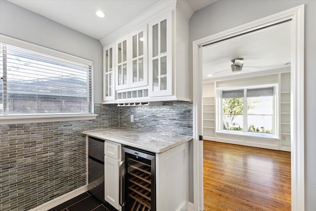 bar featuring white cabinets, light stone counters, beverage cooler, and ceiling fan