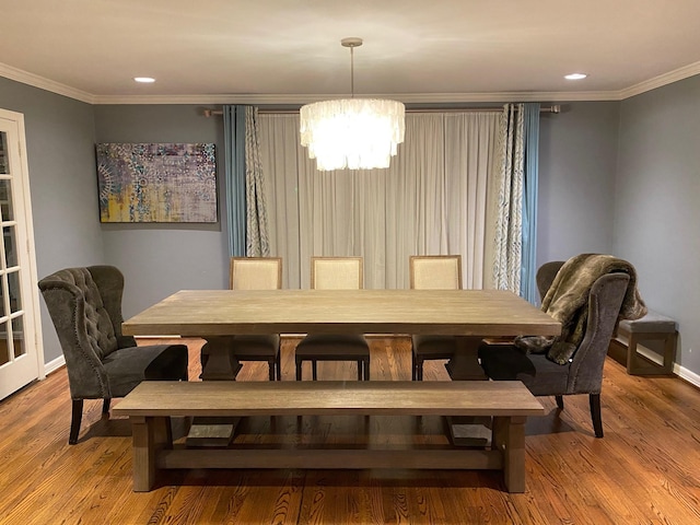 dining room with a chandelier, ornamental molding, and wood finished floors