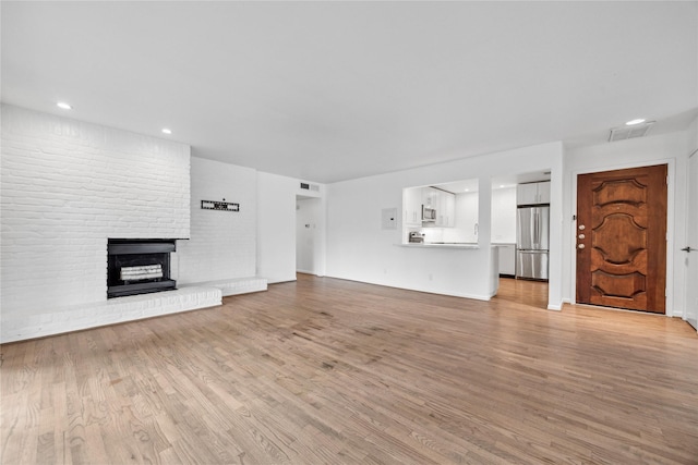 unfurnished living room with a fireplace and light hardwood / wood-style floors