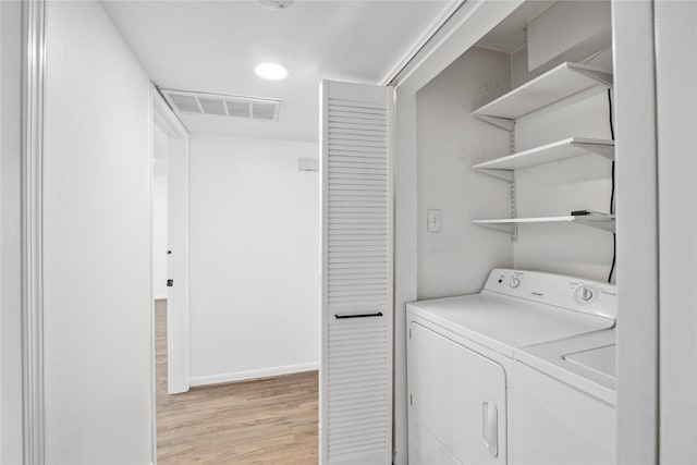 laundry room featuring washing machine and dryer and light hardwood / wood-style flooring