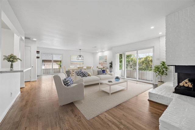 living room with hardwood / wood-style floors and a brick fireplace