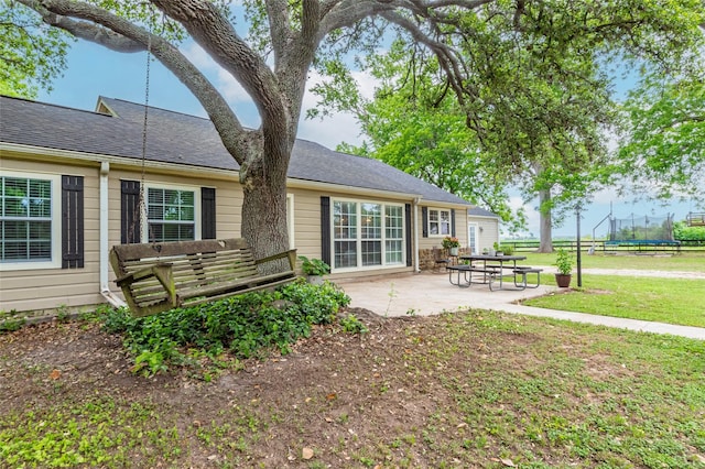 rear view of house with a yard, a patio, and a trampoline