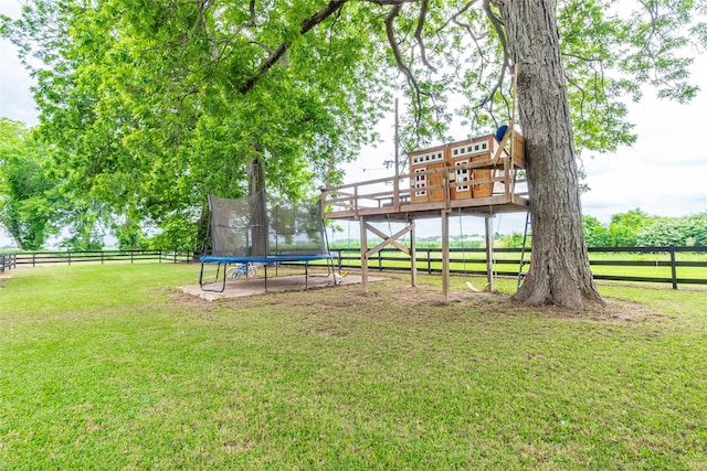 view of yard with a rural view, a trampoline, and a deck