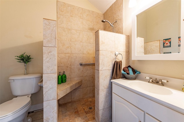 bathroom featuring tiled shower, vanity, toilet, and lofted ceiling