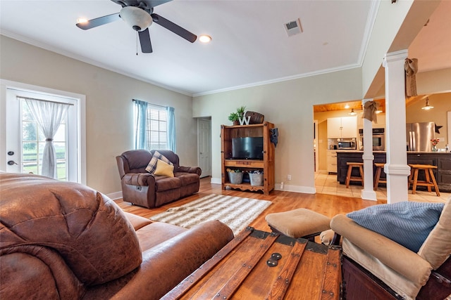 living room with ceiling fan, ornate columns, crown molding, and light hardwood / wood-style flooring