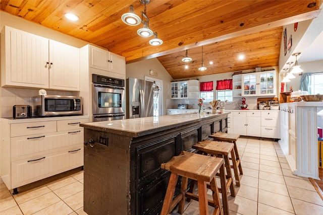 kitchen featuring pendant lighting, a kitchen island, wood ceiling, and appliances with stainless steel finishes