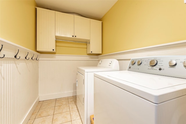 washroom featuring washing machine and clothes dryer, light tile patterned floors, and cabinets