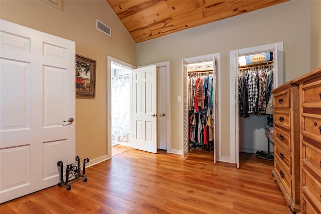 unfurnished bedroom featuring a spacious closet, light wood-type flooring, lofted ceiling, and wooden ceiling