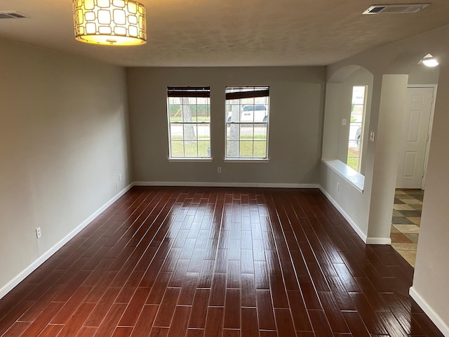 empty room with plenty of natural light and dark hardwood / wood-style floors