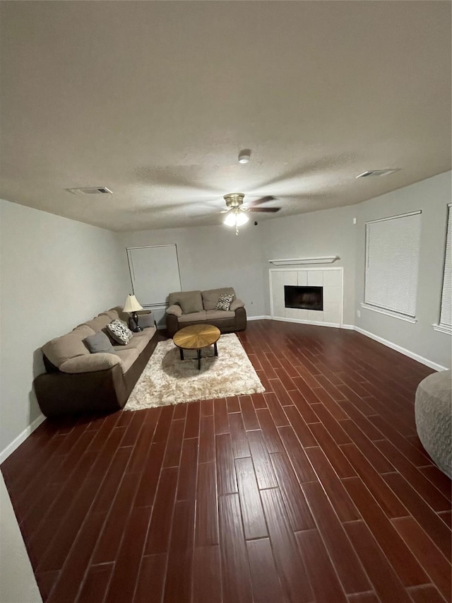 living room featuring dark hardwood / wood-style floors, ceiling fan, and a tiled fireplace