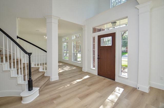 foyer entrance with light hardwood / wood-style flooring, a towering ceiling, and a notable chandelier