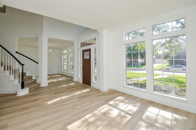 entrance foyer with decorative columns, crown molding, a chandelier, and light wood-type flooring