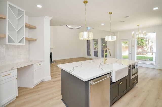 kitchen featuring white cabinetry, sink, decorative backsplash, a center island with sink, and appliances with stainless steel finishes