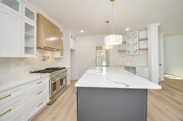 kitchen featuring white cabinets, double oven range, and an island with sink