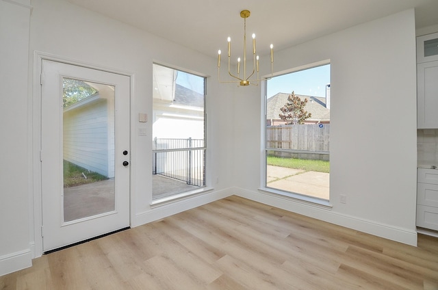 unfurnished dining area featuring a chandelier, light hardwood / wood-style flooring, and plenty of natural light