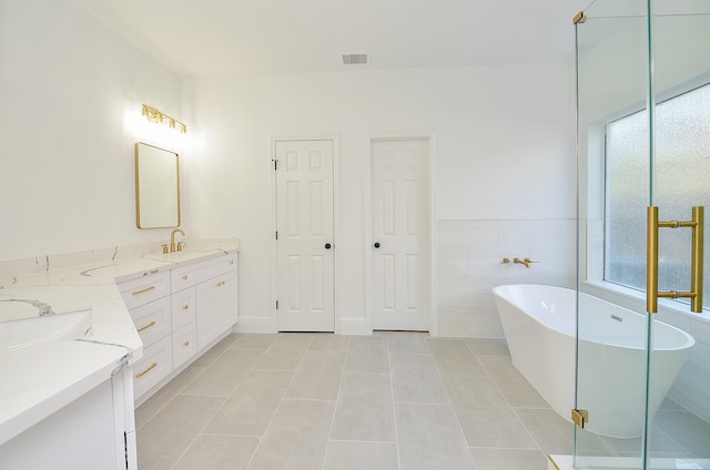 bathroom featuring tile patterned floors, vanity, independent shower and bath, and tile walls