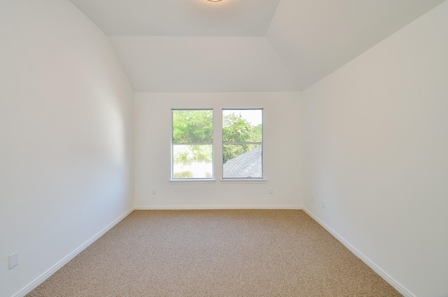 carpeted empty room with lofted ceiling