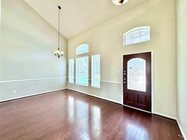 foyer entrance with dark wood-type flooring, a chandelier, and a high ceiling