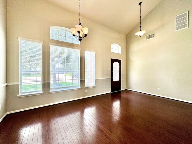 entryway with a chandelier, a towering ceiling, dark hardwood / wood-style flooring, and a wealth of natural light