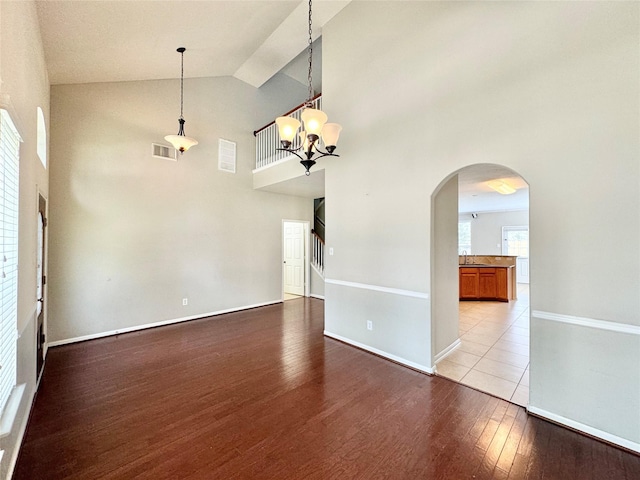 unfurnished living room featuring high vaulted ceiling, light wood-type flooring, and a notable chandelier