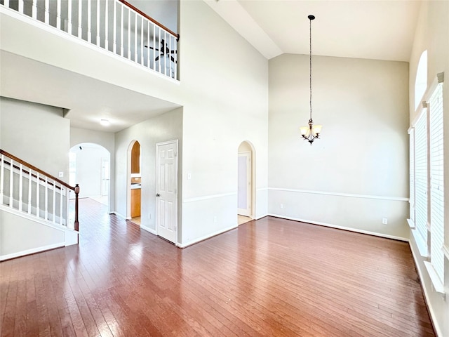 interior space with wood-type flooring, a high ceiling, and an inviting chandelier